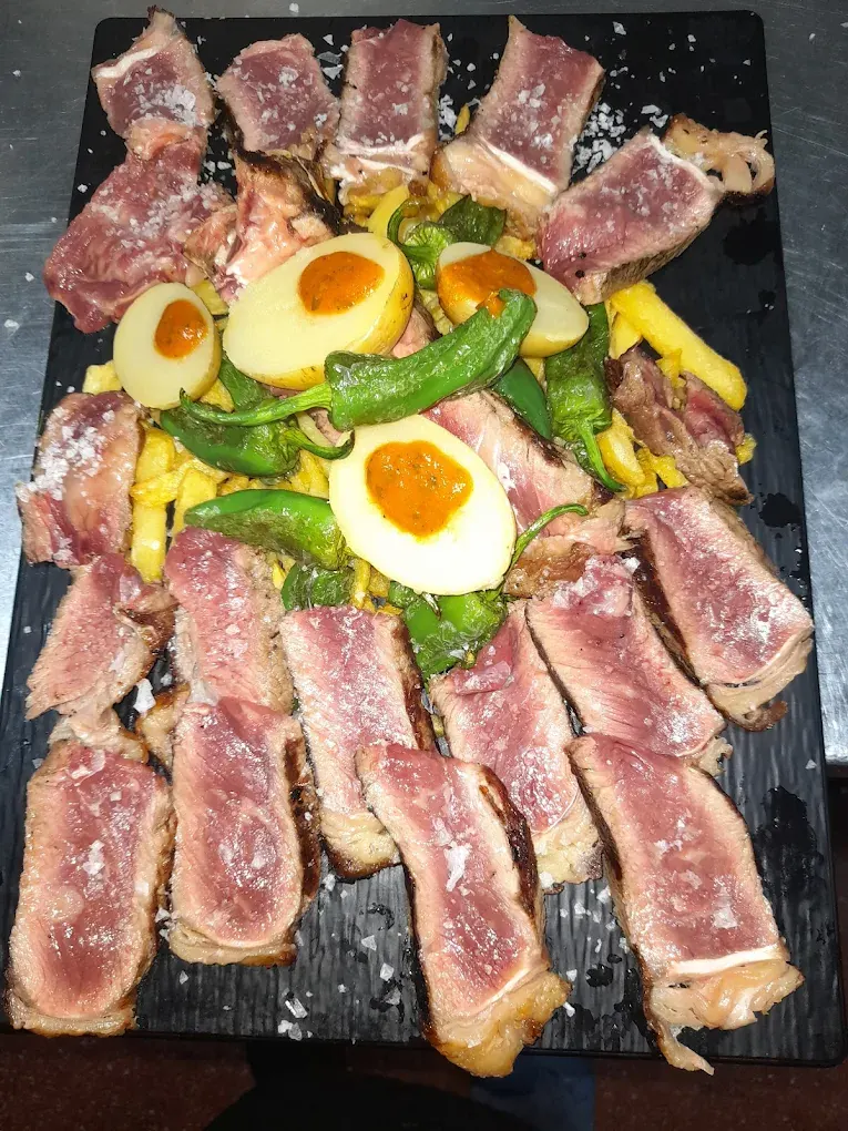 Carne a la plancha en pizarra con huevos y pimientos del gastrobar La Tita Conchi